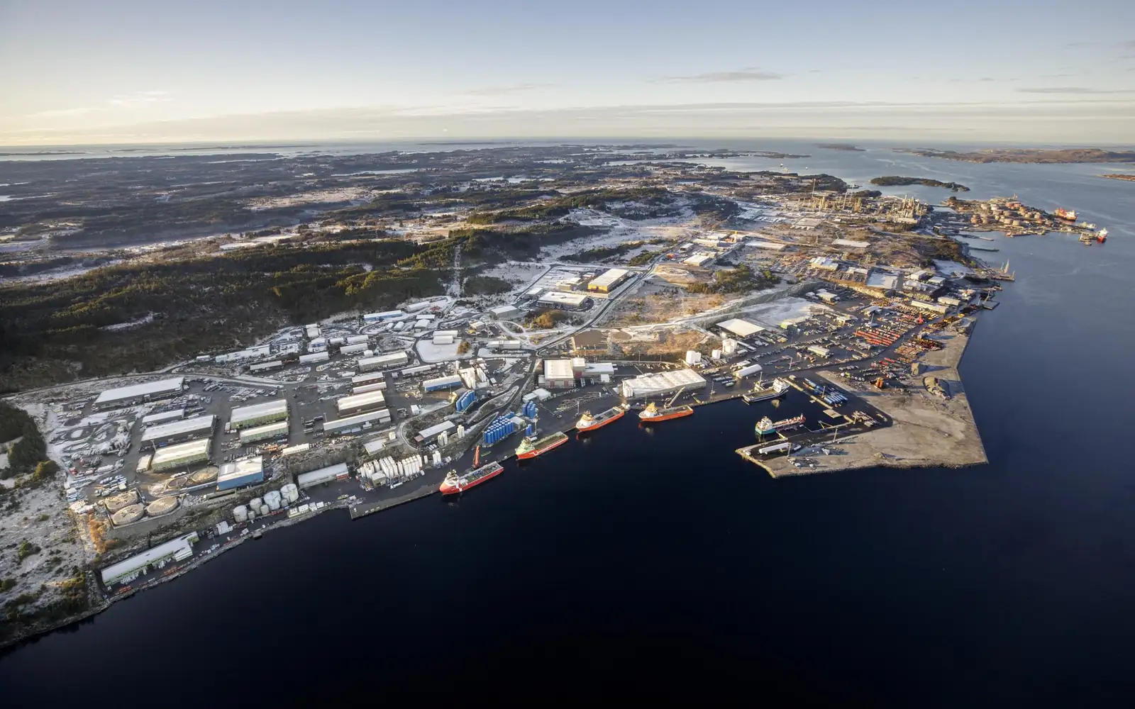 Flyfoto av Mongstad Base: kaiene med forsyningsskip, lagerhaller og uteareal