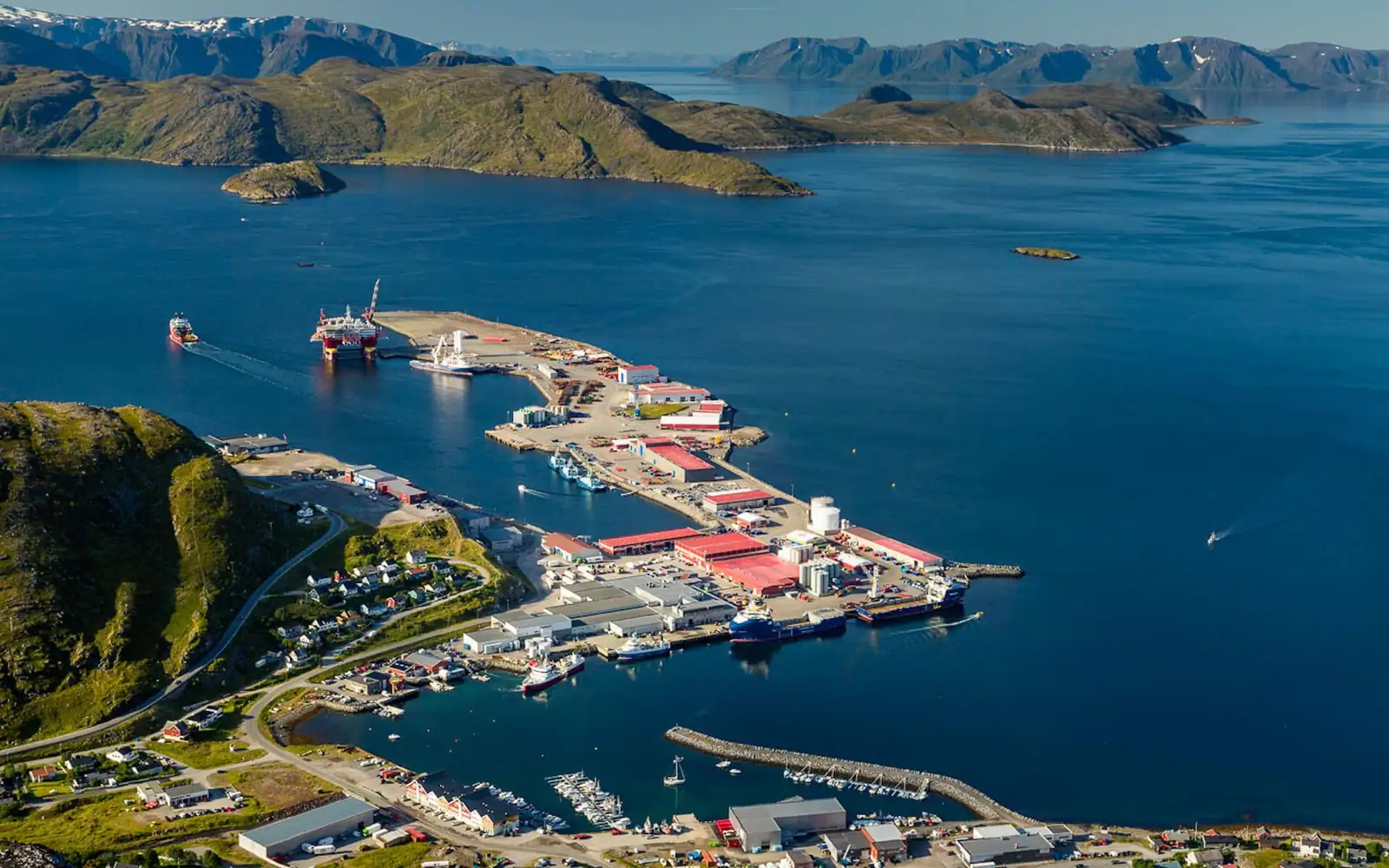 Flyfoto av Polarbase utenfor Hammerfest: kaiene og basen ved fjorden med fjellene bak